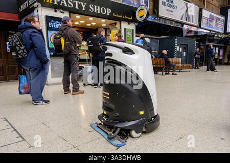 Un robot de nettoyage de sol autonome navigue parmi les voyageurs sur le hall de la gare de Charing Cross, Londres, Royaume-Uni Banque D'Images