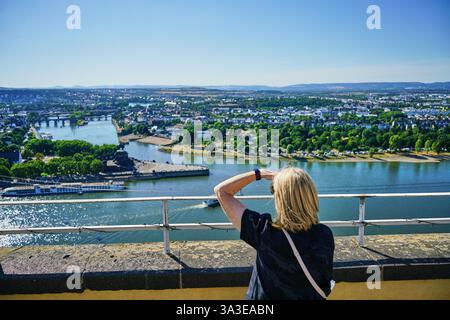 La femelle blonde jouit de la vue sur le Rhin et la Moselle au coin de l'Allemagne à Coblence, depuis la forteresse d'Ehrenbreitstein. Banque D'Images