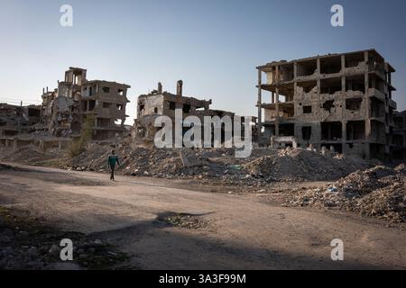 Yarmouk, Syrie. 14 mars 2025. Un homme passe devant des ruines de bâtiments déchirés par la guerre. Yarmouk était le plus grand camp de réfugiés palestiniens en Syrie. Avant la guerre, environ un million de personnes y vivaient. Aujourd'hui, il ne reste plus que des gravats et des squelettes de bâtiments. Pendant la guerre syrienne, les forces anti-régime se sont installées à Yarmouk, transformant le camp en une ligne de front pour des batailles féroces. Après la chute du régime de Bachar Al-Assad, des dizaines de personnes ont décidé de revenir, certaines pour essayer de réparer les ruines de leurs maisons, d'autres simplement pour les voir une dernière fois. Crédit : SOPA images Limited/Alamy Live News Banque D'Images