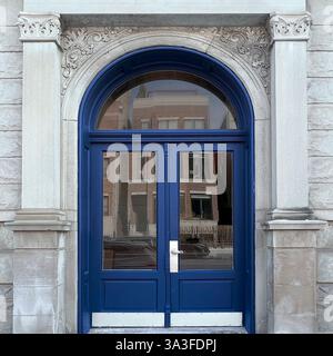 Élégantes portes doubles arquées bleu marine situées dans une façade en pierre ornée, avec des sculptures et des colonnes complexes. Banque D'Images
