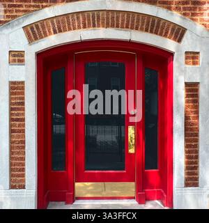 Porte arquée rouge, encadrée par une façade en brique et calcaire, reflétant le charme de l'architecture classique de Chicago. Banque D'Images