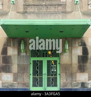 Entrée art déco ornée d'une porte en métal vert menthe ornée, de motifs géométriques, de ferronneries décoratives et d'auvent suspendu assorti. Banque D'Images