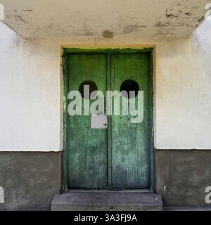 Une porte en bois vert vieilli avec des hublots ronds, mettant en valeur les influences Streamline moderne à Varsovie, en Pologne Banque D'Images