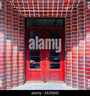 Portes doubles modernistes à Cracovie, en Pologne, encadrées par des briques vitrées rouge foncé avec des détails géométriques courbes, style du modernisme du début du XXe siècle Banque D'Images