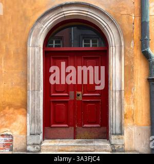 Une porte historique en bois rouge située dans une grande entrée en pierre voûtée dans la vieille ville de Varsovie, en Pologne Banque D'Images
