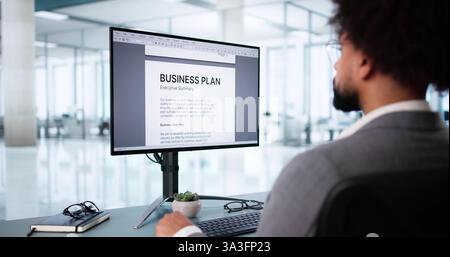 Jeune homme afro-américain remplissant le document de plan d'affaires en ligne. Banque D'Images