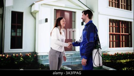 Une travailleuse amicale de lutte antiparasitaire et une femme heureuse se serrent la main à l'extérieur de la maison. Banque D'Images