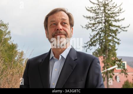 Un homme barbu en costume sourit sur fond de nature, créant une atmosphère de positivité Banque D'Images