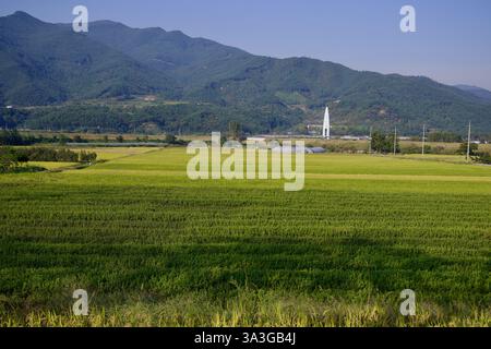 Comté de Gurye, Corée du Sud - 3 octobre 2021 : de vastes champs agricoles s'étendent vers les montagnes, avec une tour de pont blanche moderne Banque D'Images