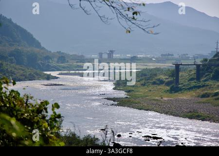 Comté de Gurye, Corée du Sud - 3 octobre 2021 : la lumière du soleil scintille à la surface de la rivière Seomjin, serpentant à travers la vallée avec le pont lointain c Banque D'Images