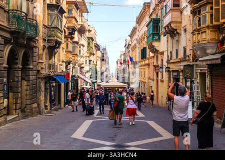 La Valette, Malte 27. Septembre 2024, les touristes prennent des photos en marchant dans une rue animée de la Valette, Malte, entourée par la traditionnelle BA maltaise Banque D'Images