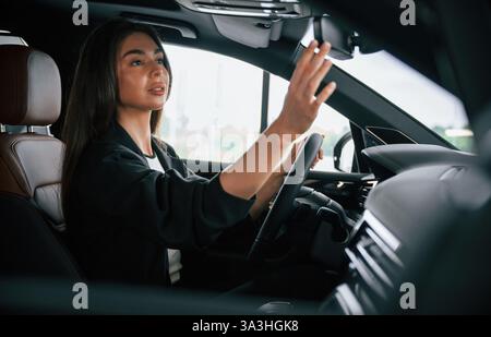 Vue de côté. Belle femme d'affaires est dans la nouvelle voiture. Banque D'Images