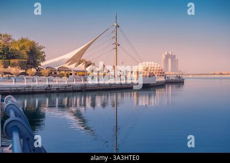 15 janvier 2025, Abu Dhabi, eau : les eaux tranquilles reflètent la ligne d'horizon moderne d'Abu Dhabi au coucher du soleil Banque D'Images