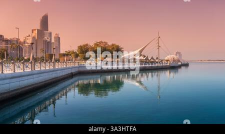 15 janvier 2025, Abu Dhabi, eau : les eaux tranquilles reflètent la ligne d'horizon moderne d'Abu Dhabi au coucher du soleil Banque D'Images