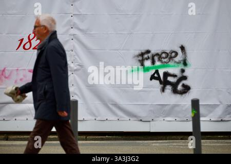 Francfort-sur-le-main, Allemagne. 14 mars 2025. Les gens passent devant un mot LIBRE peint sur une barrière en plastique entourant un bâtiment. Banque D'Images