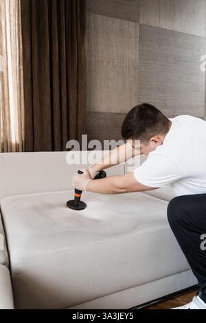 Enduire le lit de détergent à l'aide de la perceuse avec brosse pour le nettoyage à sec. Application de détergent sur le canapé à l'intérieur de la maison pour le nettoyage à sec Banque D'Images