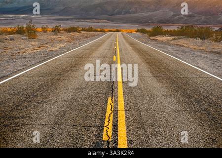 Route asphaltée à deux voies avec des montagnes en arrière-plan, perspective décroissante, parc national de la Vallée de la mort, Californie, États-Unis Banque D'Images
