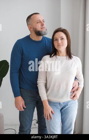l'homme et la femme se tiennent ensemble, s'embrassant dans un environnement familial chaleureux. Couple partage un moment d'affection, représentant l'amour et les liens familiaux Banque D'Images