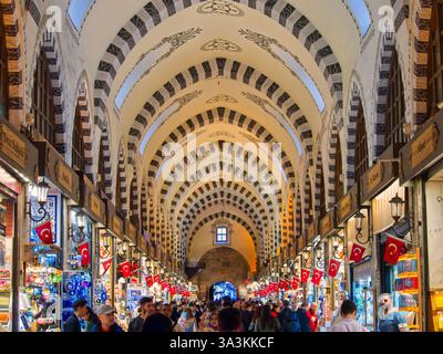 Instanbul, Turquie - 1er mai 2024 : intérieur arqué orné d'un bazar turc animé avec des magasins, des drapeaux et des foules de gens qui font du shopping Banque D'Images