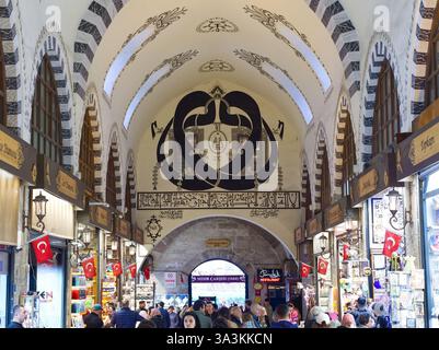 Instanbul, Turquie - 1er mai 2024 : intérieur arqué orné d'un bazar turc animé avec boutiques, architecture décorative et drapeaux nationaux Banque D'Images
