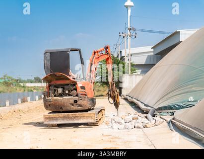 Excavatrice sur chenilles avec marteau de marteau hydraulique pour la destruction de la route en béton à l'usine. Banque D'Images