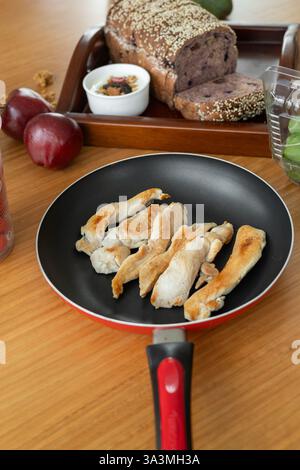 Un repas sain composé de poulet tendre, d'une pomme croustillante et d'une tranche de pain frais, le tout magnifiquement disposé sur une table en bois. Ce combin équilibré Banque D'Images