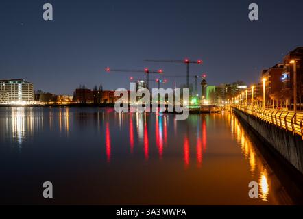 Berlin, Allemagne. 17 mars 2025. Les grues d'un chantier près de la gare d'Ostkreuz à Berlin se reflètent dans l'eau du lac Rummelsburg. L'Institut de recherche économique de l'ifo présentera ses prévisions économiques pour le printemps 2025 lors d'une conférence de presse. Crédit : Soeren Stache/dpa/Alamy Live News Banque D'Images