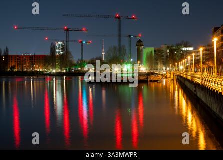 Berlin, Allemagne. 17 mars 2025. Les grues d'un chantier près de la gare d'Ostkreuz à Berlin se reflètent dans l'eau du lac Rummelsburg. L'Institut de recherche économique de l'ifo présentera ses prévisions économiques pour le printemps 2025 lors d'une conférence de presse. Crédit : Soeren Stache/dpa/Alamy Live News Banque D'Images