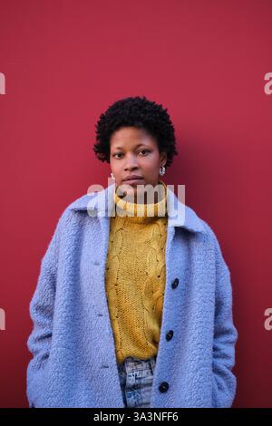 Jeune femme posant devant un mur rouge Banque D'Images