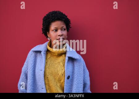 La jeune femme pose devant le mur rouge Banque D'Images