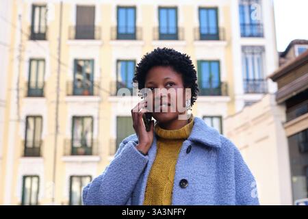 Jeune femme noire parlant au téléphone marchant dans la rue de Madrid Banque D'Images