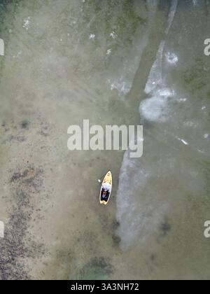 Vue aérienne d'un paddleboarder sur un lac partiellement gelé. Banque D'Images