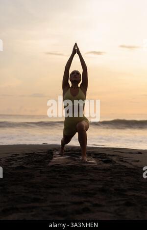 L'INDONÉSIE, Bali, woman practicing yoga sur la côte Banque D'Images