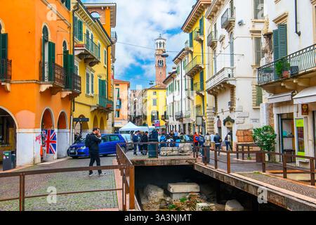 Vérone, Italie. Rues piétonnes de bâtiments colorés avec boutiques de luxe et boutiques, restaurants et cafés sur le trottoir dans la vieille ville historique Banque D'Images