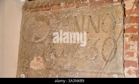 16 mars 2025 - Neubruchhausen-Allemagne : Grande pierre gravée marquant la construction d'un moulin à eau historique en 1730, construit dans un mur de briques. Banque D'Images