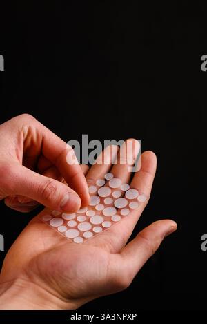 Patchs d'acné pour se débarrasser des zits problématiques sur la peau irritée sans médicaments. Soin de la peau avec des patchs de bouton d'acné sur fond noir Banque D'Images
