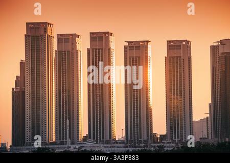 21 janvier 2025, Abu Dhabi, eau : coucher de soleil entre les gratte-ciel modernes reflétant une lumière orange chaude Banque D'Images