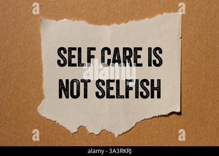 Self Care n'est pas un message égoïste écrit sur un morceau de papier déchiré déchiré sur fond brun. L'autosoin conceptuel n'est pas un symbole égoïste. Copier l'espace. Banque D'Images