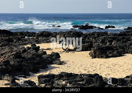 Une bicyclette solitaire appuyée contre des roches volcaniques au bord de la mer, Fuerteventura, îles Canaries, Espagne, Europe, UE Banque D'Images