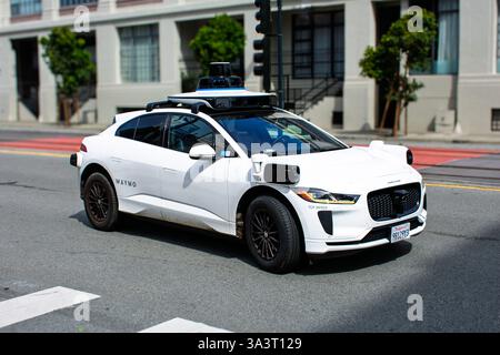 Waymo Jaguar I-PACE équipé de la technologie de conduite autonome navigue dans une intersection de ville, des capteurs visibles et des caméras - San Francisco, Californie, États-Unis Banque D'Images
