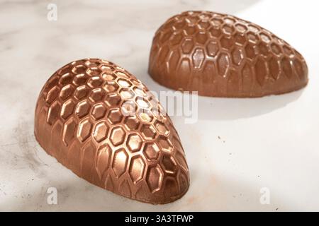 Oeuf de Pâques en chocolat avec texture en nid d'abeilles décoré de poudre de cuivre comestible. Banque D'Images