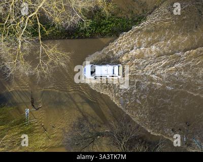 Une voiture traverse les eaux de crue au Billing Aquadrome dans le Northamptonshire. La tempête Bert continuera d'entraîner des perturbations lundi après des pluies torrentielles qui ont provoqué des inondations « dévastatrices » au cours du week-end. Date de la photo : lundi 25 novembre 2024. Banque D'Images