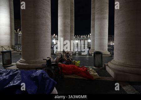 Cité du Vatican, Italie. 17 mars 2025. Cité du Vatican, Italie 17.03.2025 : un sans-abri en fauteuil roulant dort sur le toit sous la colonnade de Pierre, sur la tente l'écriture Dieu vous bénisse. Crédit : Agence photo indépendante/Alamy Live News Banque D'Images