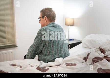 Homme assis sur le lit. Banque D'Images