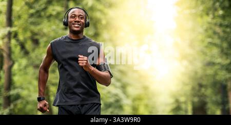Joyeux gars noir jogging dans la forêt d'été Banque D'Images