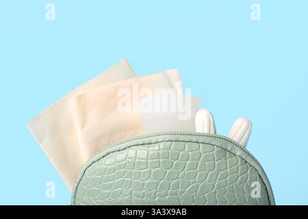 Sac cosmétique Lady's avec coupe menstruelle, coussinets et tampons sur fond bleu Banque D'Images