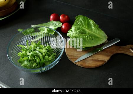 Vue de dessus de laitue romaine verte fraîche sur planche à découper en bois et dans un bol Banque D'Images