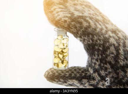 La vitamine d vous garde en bonne santé tout en manquant de soleil dans les pays nordiques en hiver. Capsules de d-vitamine jaune à coquille molle contre la neige blanche dans un pot en verre. Banque D'Images