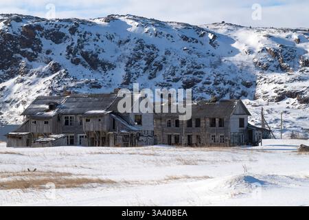 Vieilles maisons abandonnées dans le village arctique de Teriberka par une journée ensoleillée de mars. Région de Mourmansk, Russie Banque D'Images