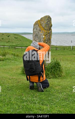 Photographe / touriste prenant une photo de la pierre de comète sur le ring du site Brodgar, Orcades Écosse mai Banque D'Images